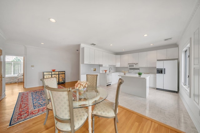 dining space featuring light hardwood / wood-style floors and crown molding