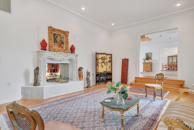 living room featuring a high end fireplace, hardwood / wood-style flooring, and crown molding