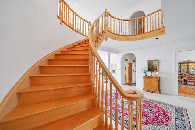 stairs with a high ceiling, decorative columns, and a healthy amount of sunlight