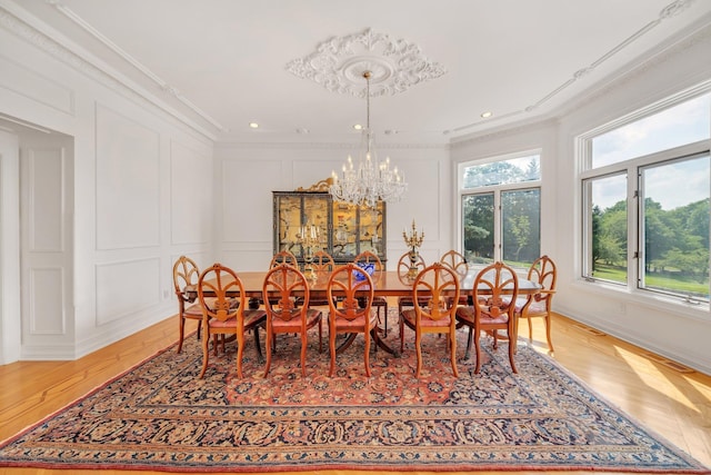 dining room with an inviting chandelier, light hardwood / wood-style floors, and crown molding