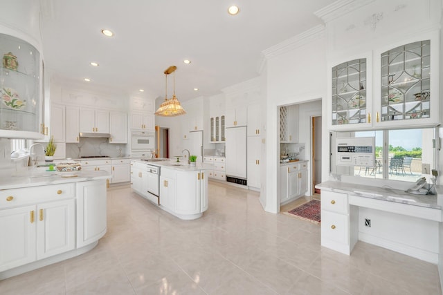 kitchen featuring hanging light fixtures, decorative backsplash, white cabinets, white appliances, and a kitchen island with sink