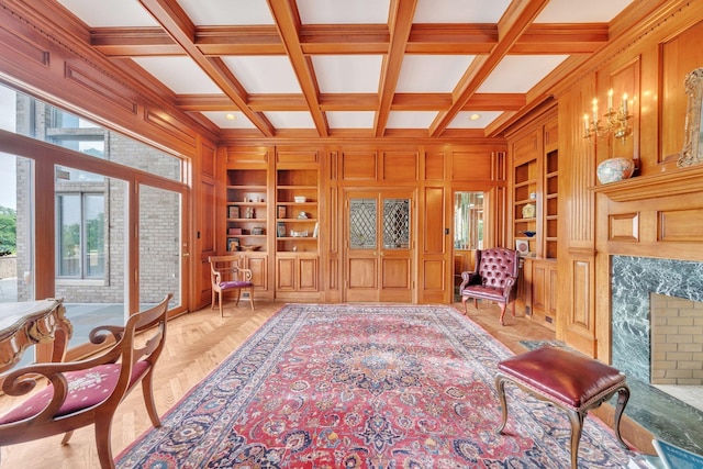 sitting room with built in shelves, wood walls, beam ceiling, and coffered ceiling