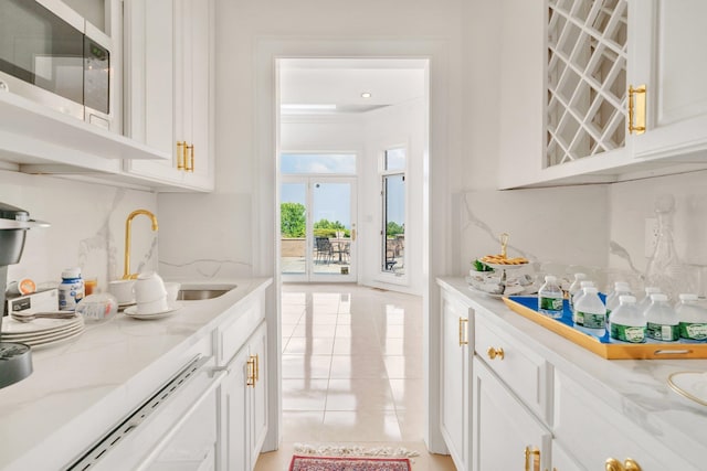 bar with white cabinets, light tile patterned flooring, light stone counters, and ornamental molding