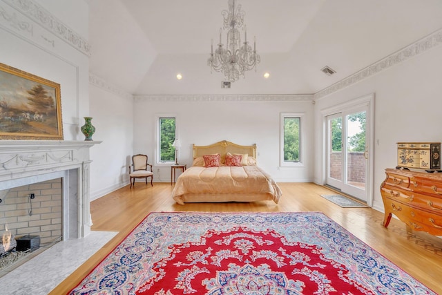 bedroom with light hardwood / wood-style floors, an inviting chandelier, vaulted ceiling, and access to outside