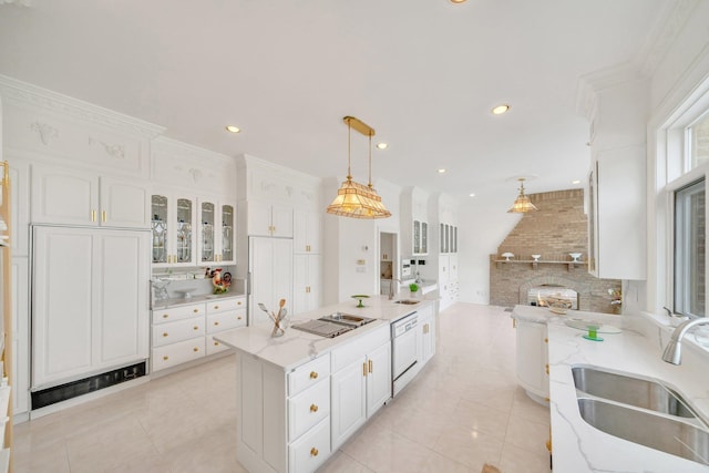 kitchen featuring a brick fireplace, white cabinets, hanging light fixtures, sink, and light stone countertops