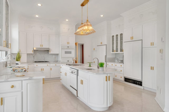 kitchen with white cabinetry, pendant lighting, sink, an island with sink, and white appliances