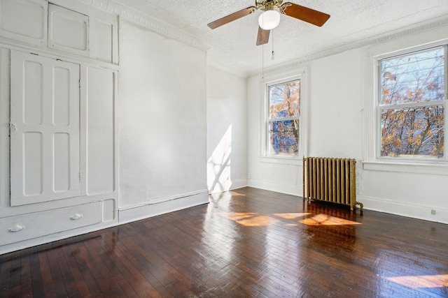 spare room with crown molding, radiator heating unit, a textured ceiling, baseboards, and hardwood / wood-style flooring