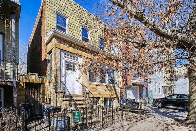 view of property featuring a fenced front yard, entry steps, brick siding, and driveway