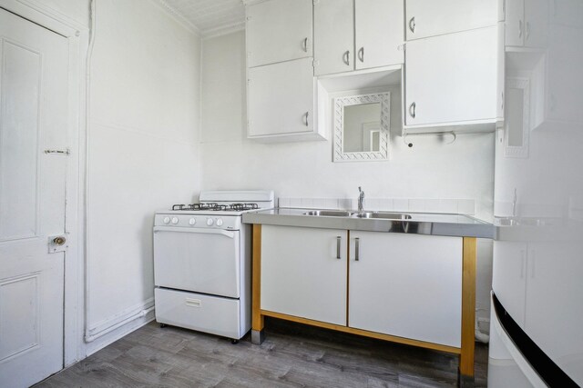 kitchen featuring a sink, wood finished floors, white cabinetry, light countertops, and gas range gas stove