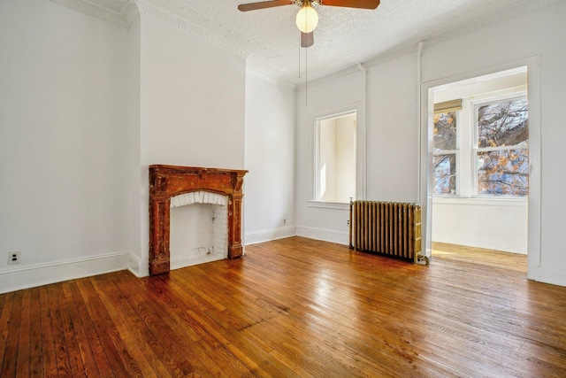 unfurnished living room with hardwood / wood-style flooring, radiator heating unit, and a fireplace