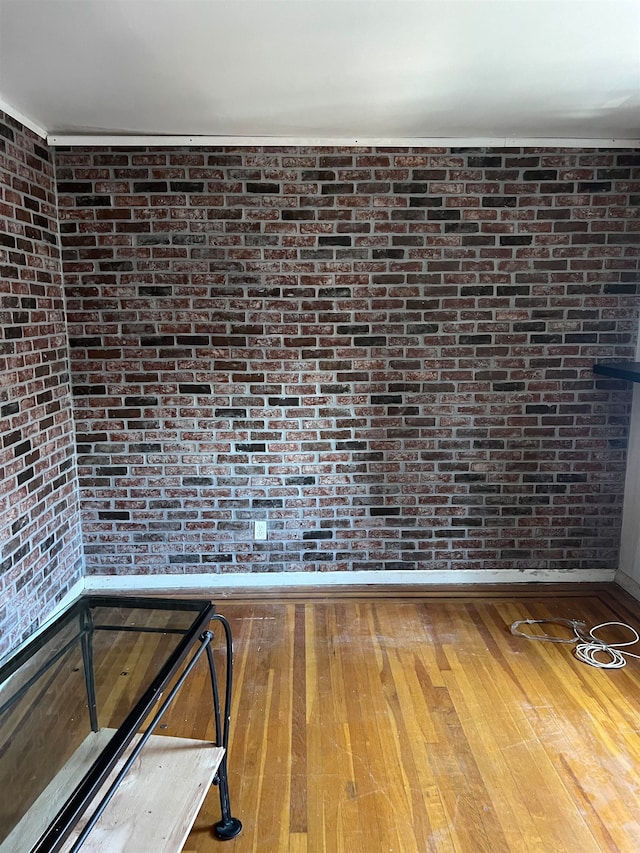 interior space featuring hardwood / wood-style floors and brick wall