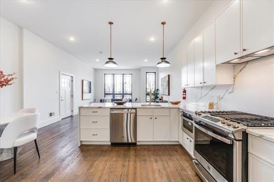 kitchen featuring dark wood-style floors, white cabinets, a peninsula, and stainless steel appliances