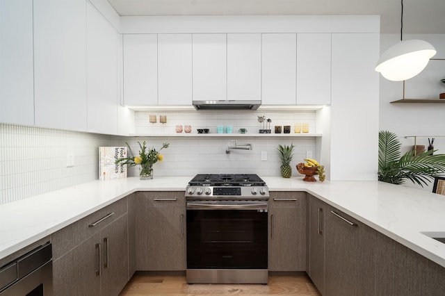 kitchen with light hardwood / wood-style flooring, stainless steel gas range, light stone countertops, decorative light fixtures, and white cabinetry