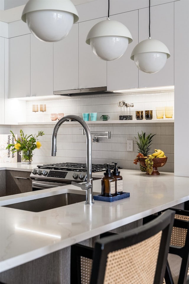 kitchen with backsplash, white cabinetry, light stone countertops, and pendant lighting