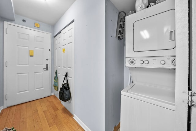 washroom with stacked washing maching and dryer and light wood-type flooring