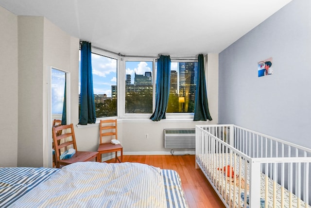 bedroom with light hardwood / wood-style flooring and a wall mounted AC