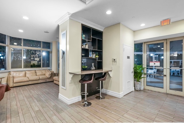 bar featuring built in shelves, light wood-type flooring, french doors, and ornamental molding