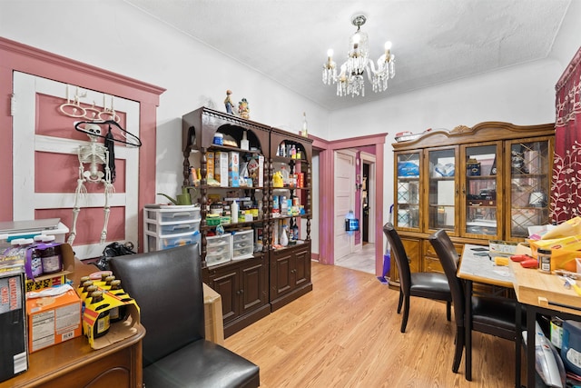 home office with a notable chandelier, light hardwood / wood-style flooring, and a textured ceiling