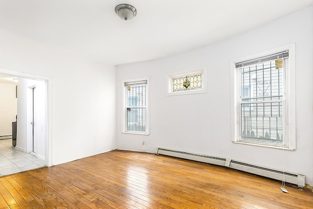 unfurnished room featuring a baseboard heating unit, a baseboard radiator, and light wood-style flooring