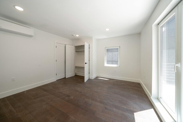 unfurnished bedroom featuring dark wood-type flooring and a wall mounted air conditioner