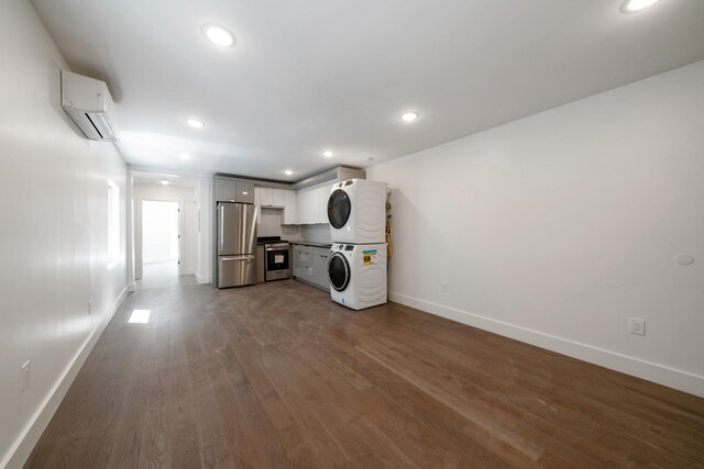 clothes washing area featuring a wall unit AC, stacked washer and clothes dryer, and dark hardwood / wood-style flooring