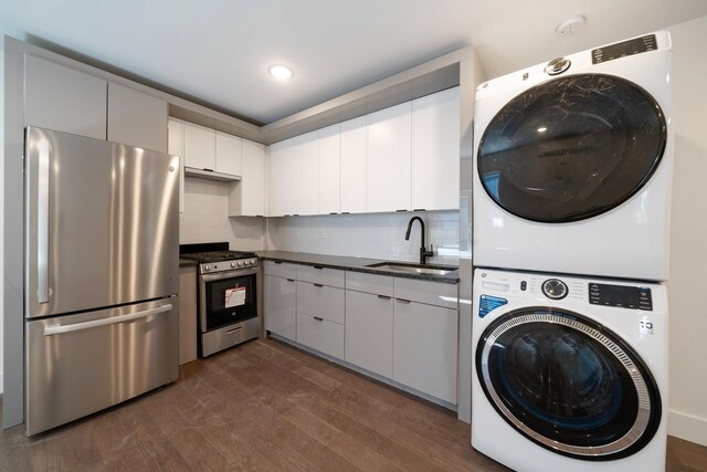 clothes washing area featuring dark wood-type flooring, stacked washer / dryer, and sink