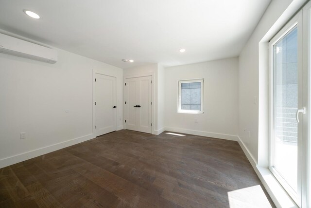 spare room with dark wood-type flooring and a wall mounted air conditioner