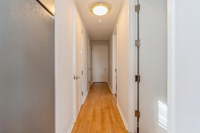 hall featuring light wood finished floors and baseboards