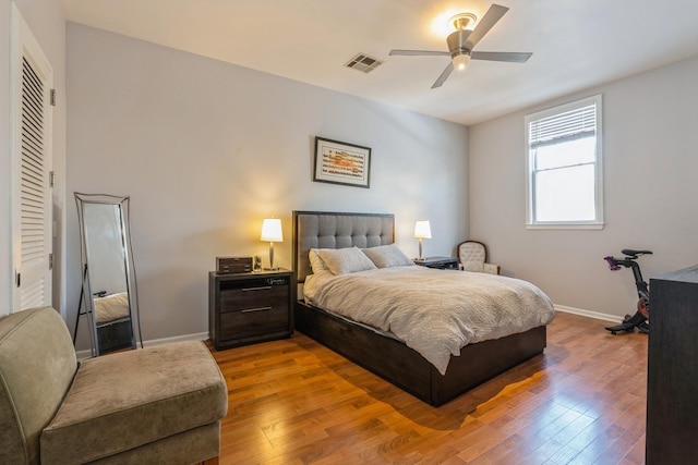 bedroom with ceiling fan, wood finished floors, visible vents, and baseboards