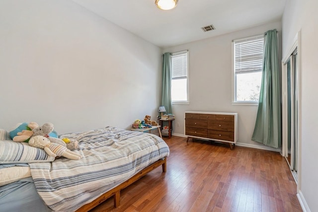 bedroom featuring wood finished floors, visible vents, and baseboards