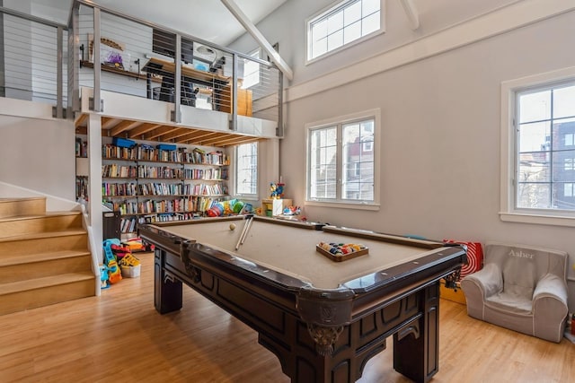 playroom featuring light wood-style floors, a wealth of natural light, and a towering ceiling