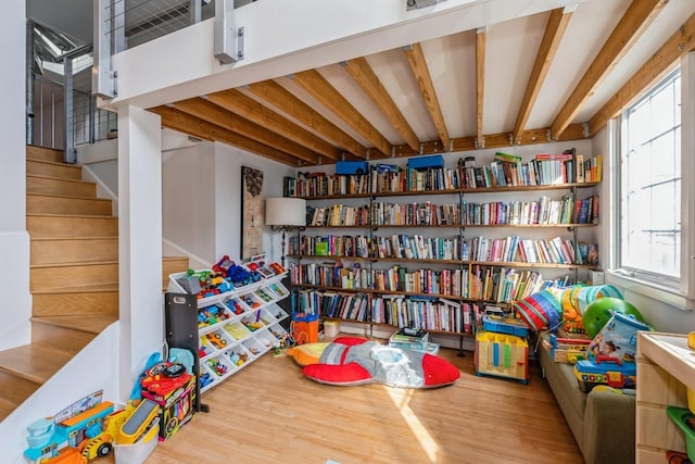 rec room with wood finished floors, a wealth of natural light, and beamed ceiling