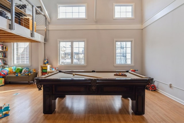 recreation room with a high ceiling, plenty of natural light, and light wood-style floors