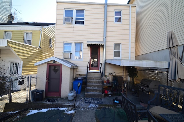 back of house featuring entry steps, a shed, fence, and an outdoor structure