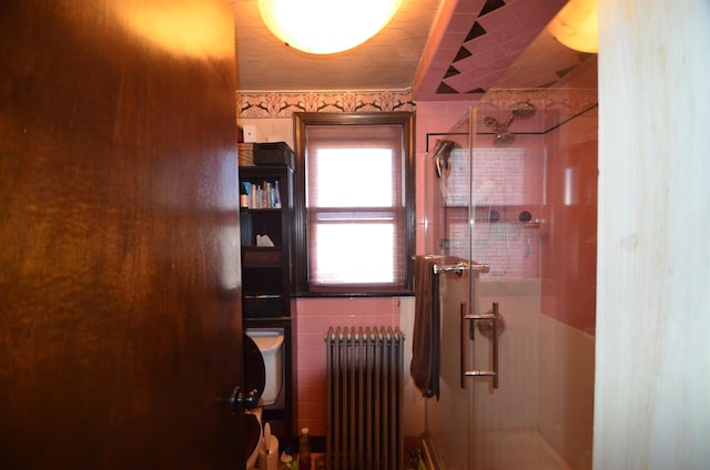 bathroom with a shower stall, tile walls, and radiator