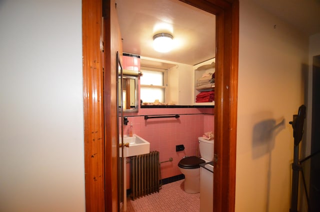 bathroom with radiator, toilet, tile walls, and tile patterned floors