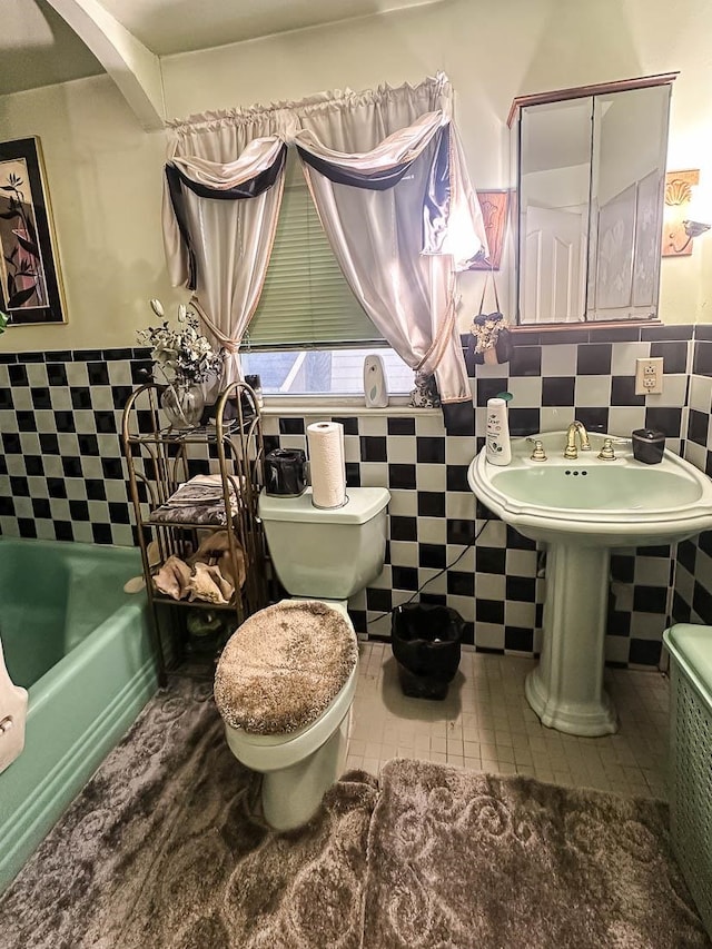 bathroom with tile patterned floors, toilet, tile walls, and a tub