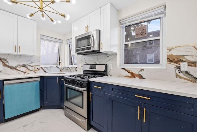 kitchen with white cabinets, blue cabinets, sink, decorative backsplash, and stainless steel appliances