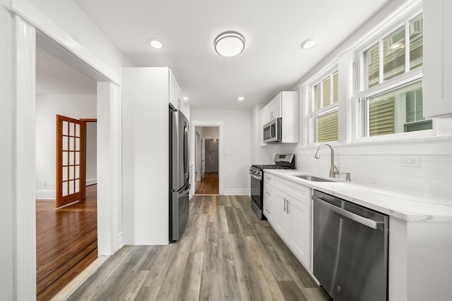 1007 88th St, North Bergen, NJ 07047 - kitchen featuring stainless steel appliances, light wood-style flooring, white cabinets, decorative backsplash, and recessed lighting