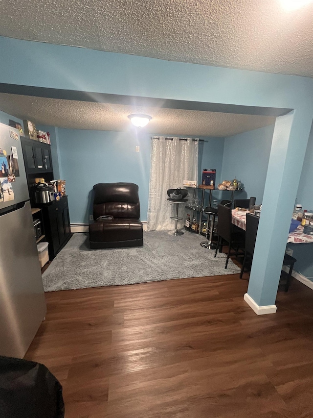 living room with a baseboard heating unit, dark hardwood / wood-style floors, and a textured ceiling