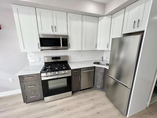 kitchen with white cabinetry, sink, light hardwood / wood-style floors, and appliances with stainless steel finishes