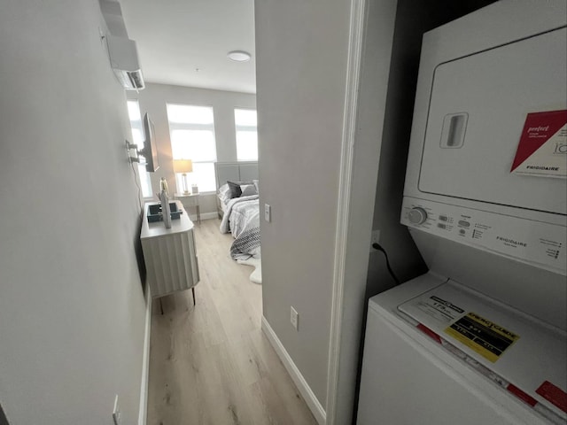 laundry area featuring stacked washer and dryer and light wood-type flooring