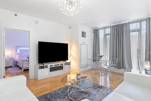 living room with visible vents, light wood-style floors, and an inviting chandelier