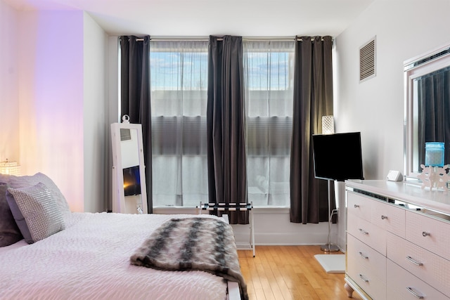 bedroom with light wood finished floors, baseboards, and visible vents