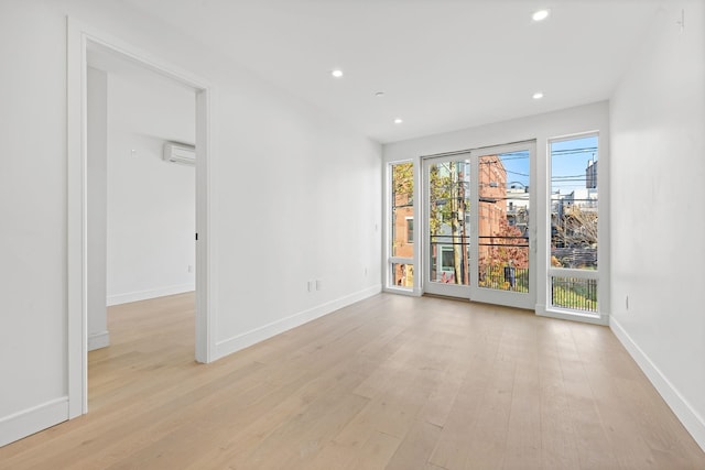 spare room featuring light hardwood / wood-style floors and a wall unit AC