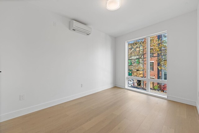 spare room featuring an AC wall unit and light hardwood / wood-style flooring