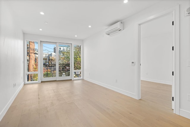 spare room with a wall unit AC and light hardwood / wood-style flooring