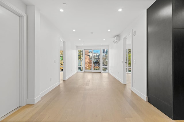 corridor with light hardwood / wood-style floors and a wall mounted AC