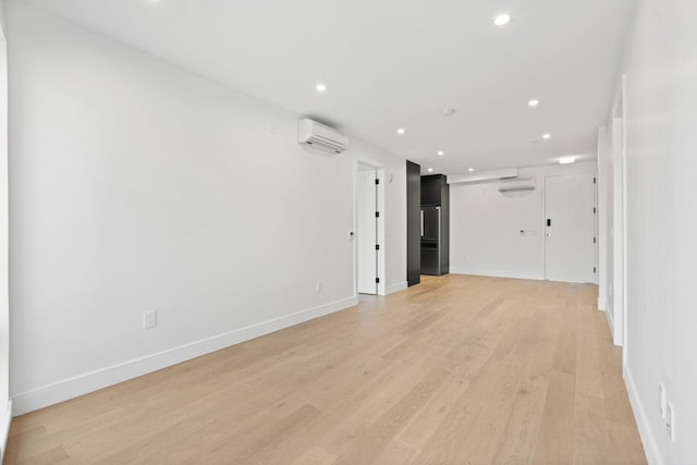 unfurnished room with light wood-type flooring and an AC wall unit