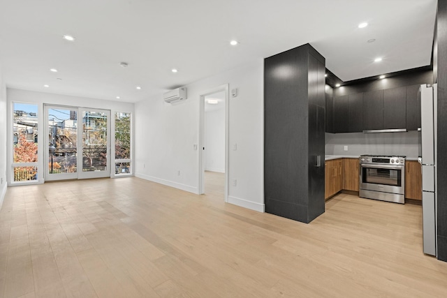 kitchen with light hardwood / wood-style flooring, a wall mounted AC, and stainless steel gas range